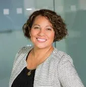 A brown women with a smile with black shirt and black and white upper